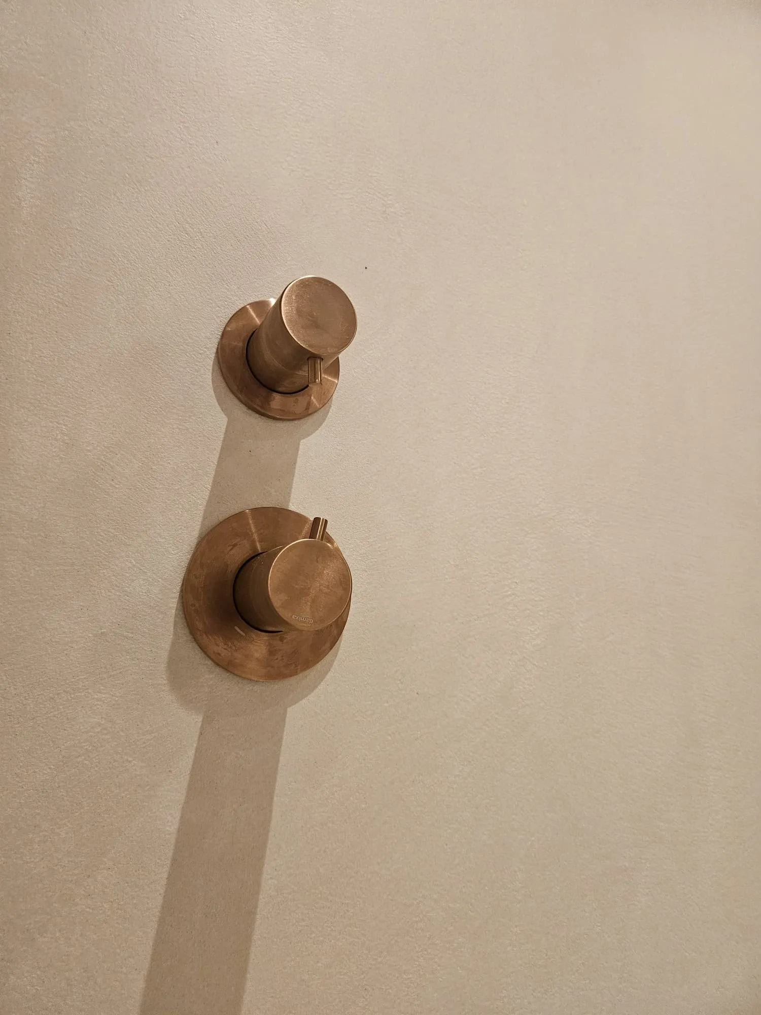 Koperen douchekranen op een wand van microcement, van dichtbij
