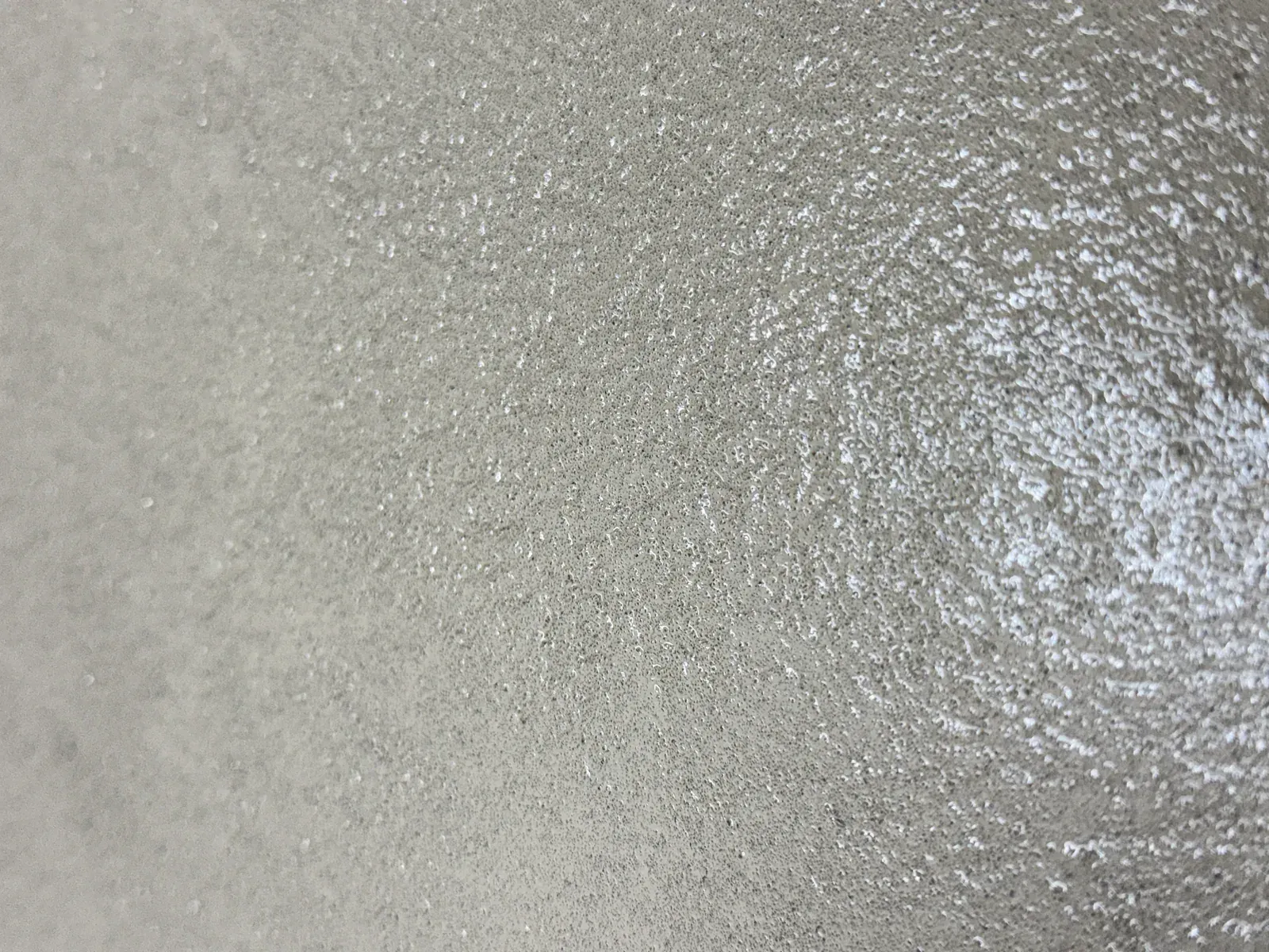 Detail van de subtiele korrel en lichtreflectie in een lichtgrijze lavasteen vloer