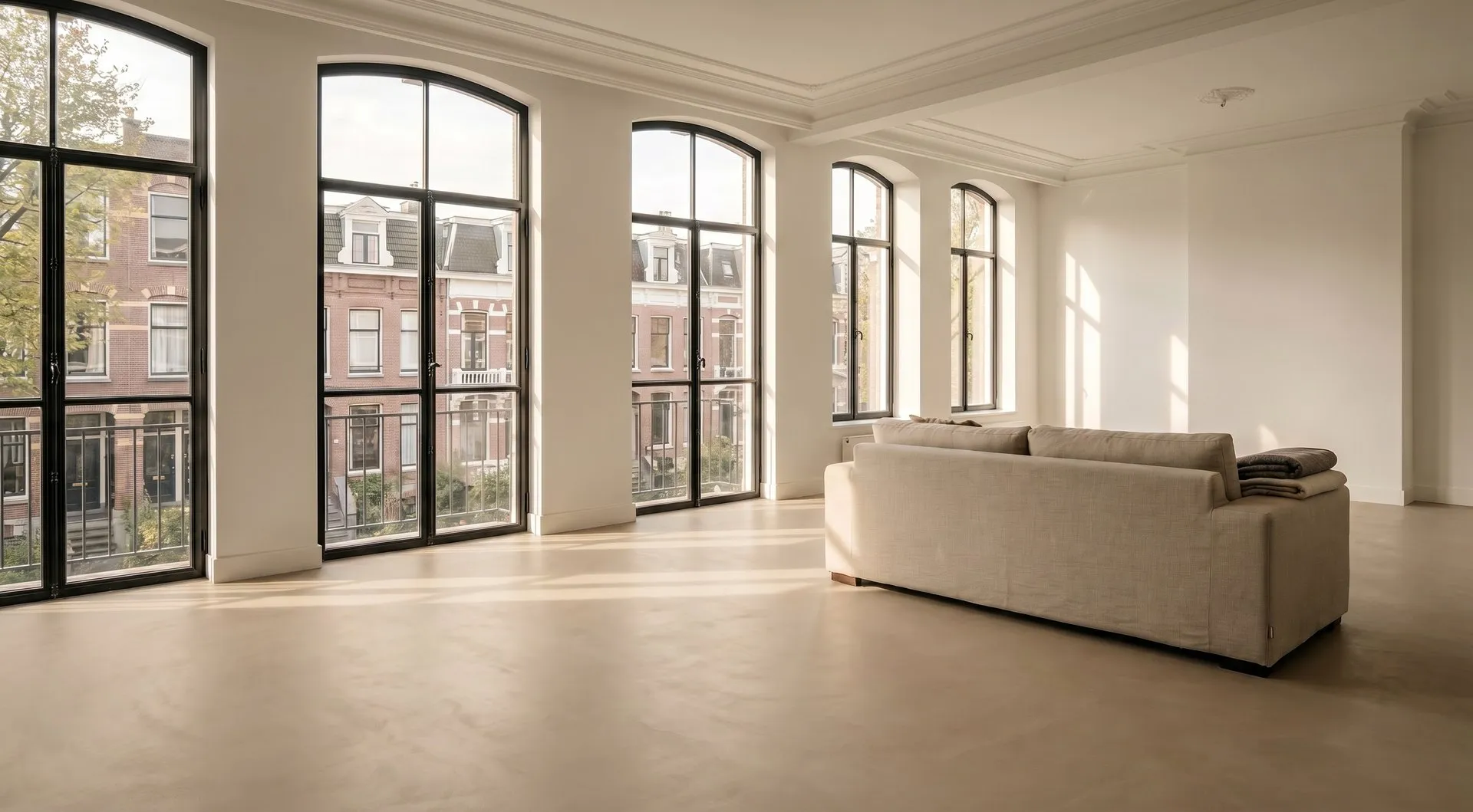 Na: dezelfde woonkamer met een naadloze microcement vloer in een warme zandtint