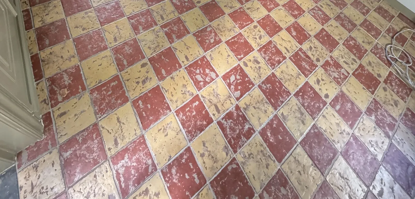 Vóór: de oude rood-gele plavuizenvloer in de woonkeuken, met voegen en slijtplekken